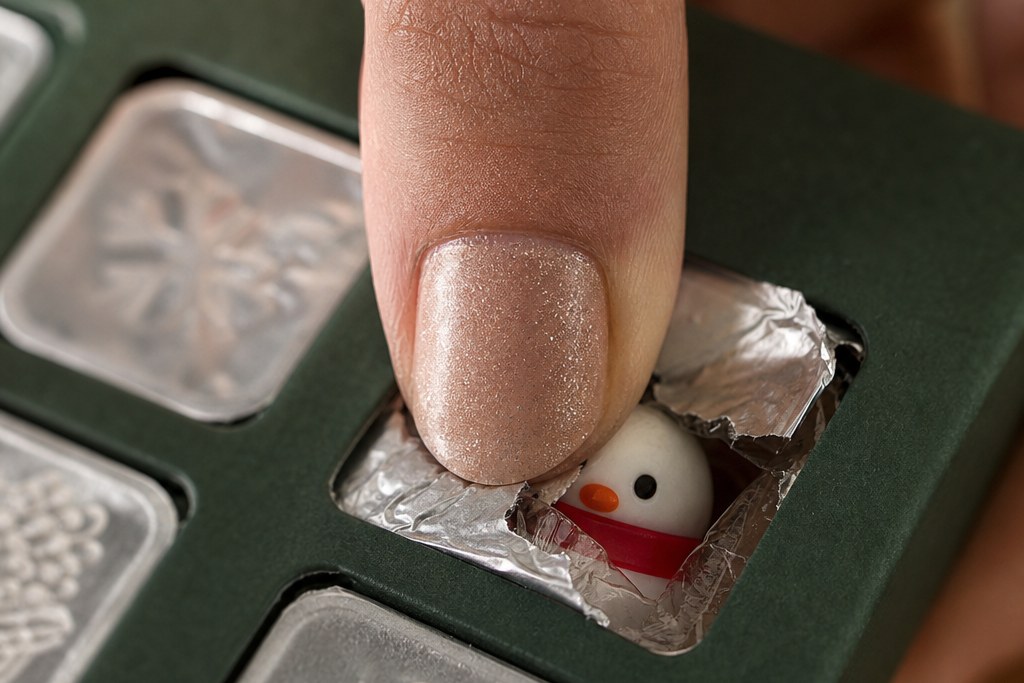 A thumb pressing through the foil seal of one calendar cell