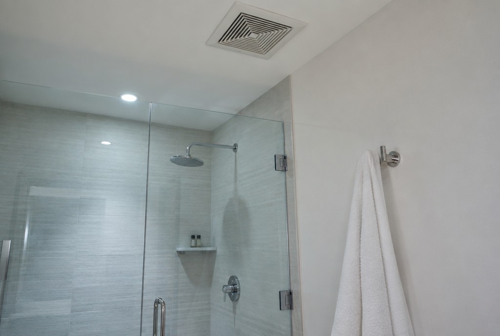 Hotel bathroom with a glass shower, ceiling vent and towel hook